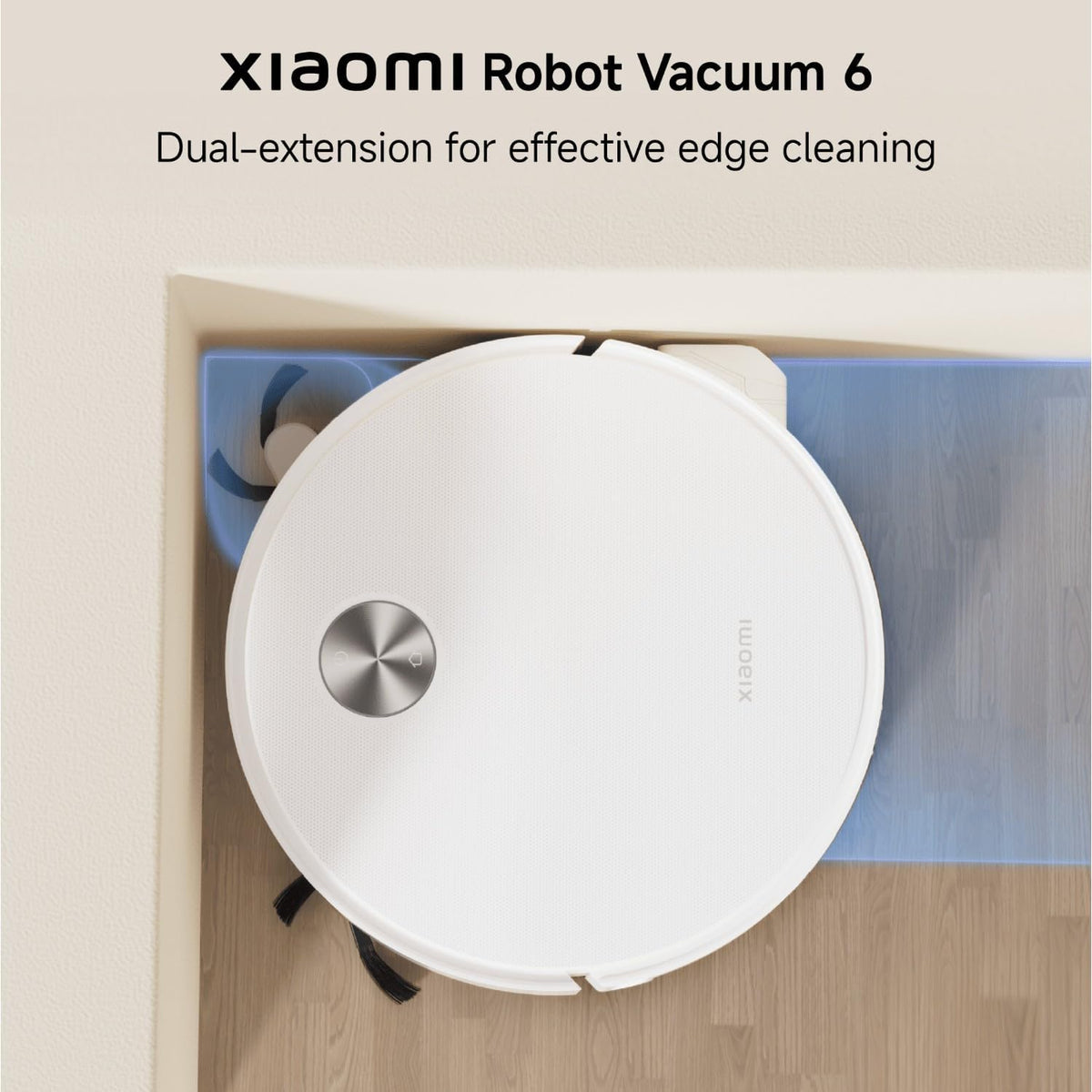 Xiaomi Robot Vacuum 6 shown from above in a home setting, navigating a corner with a blue floor extension. The vacuum is white with a silver metallic button on top.