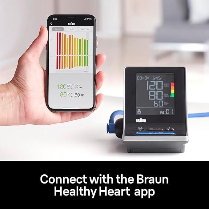 Braun upper arm blood pressure monitor with Bluetooth connectivity, shown with a smartphone displaying the Braun Healthy Heart app.