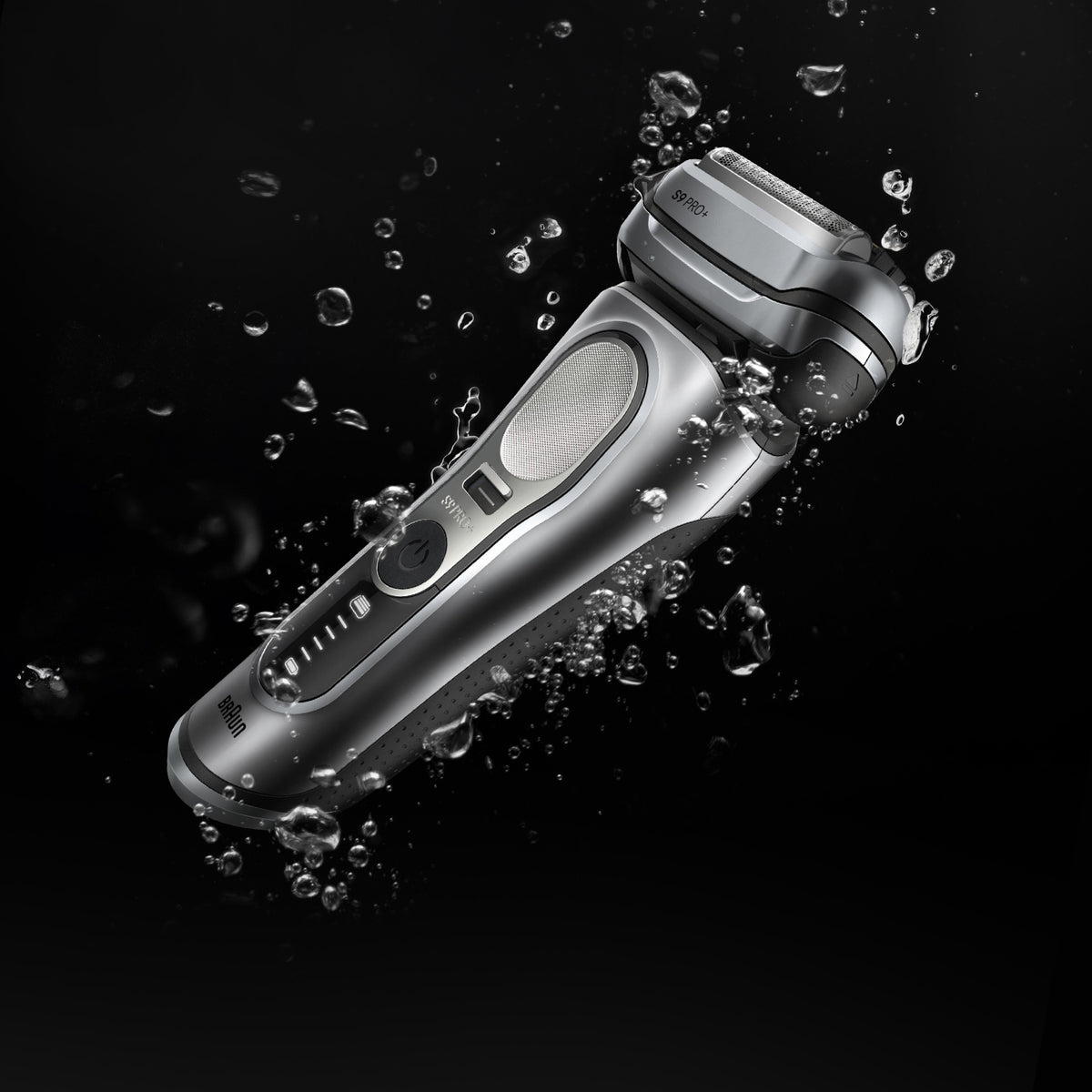 Silver electric shaver with water droplets on a black background