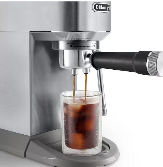 Taghareed De'Longhi Dedica Duo stainless steel espresso machine brewing cold brew coffee into a glass with ice.