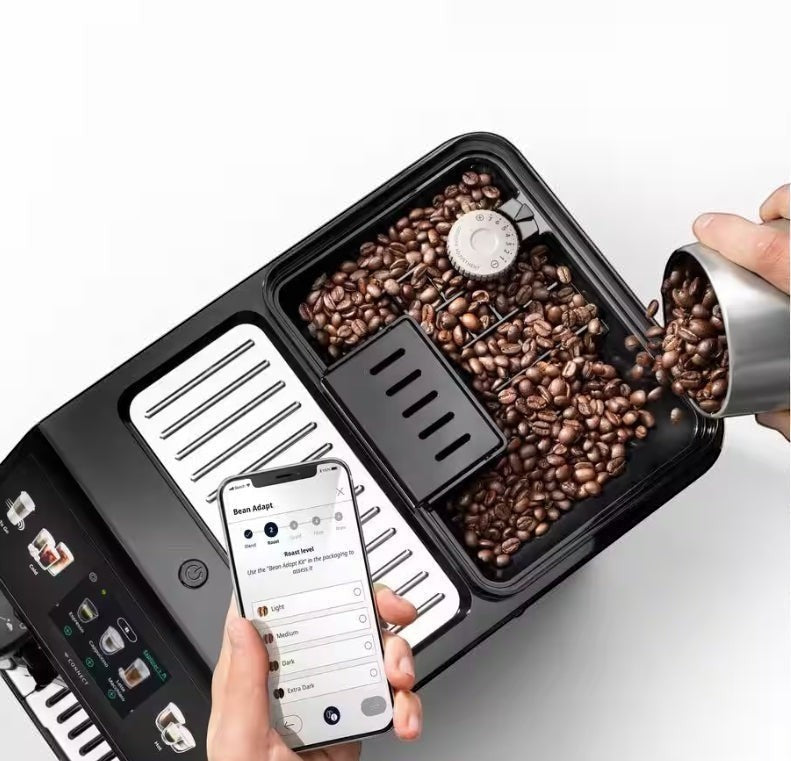 Taghareed De’Longhi Eletta Explore coffee machine with beans and a smartphone showing the Bean Adapt app.
