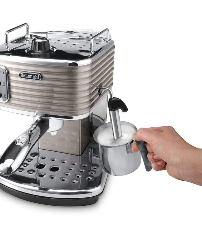 Taghareed De'Longhi Scultura espresso machine in beige with chrome accents, frothing milk in a stainless steel pitcher.