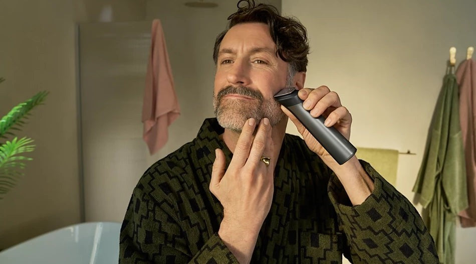 Taghareed man grooming beard with Philips All-in-One Trimmer 7000 Series MG7922/15, featuring 13 attachments and BeardSense technology.