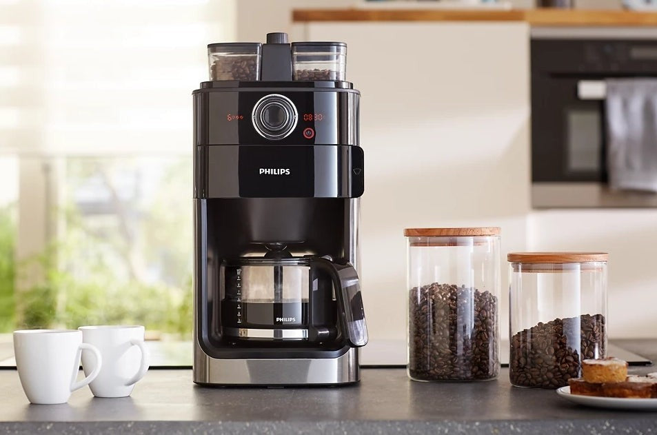 Taghareed Philips Grind & Brew coffee maker with built-in grinder, dual bean container, and glass carafe. Black and silver.
