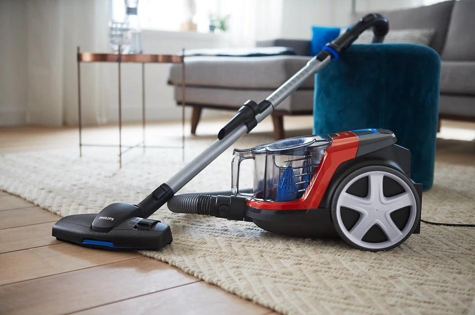 Taghareed Philips PowerPro Compact bagless vacuum cleaner in red and black with a MultiClean nozzle on a rug.