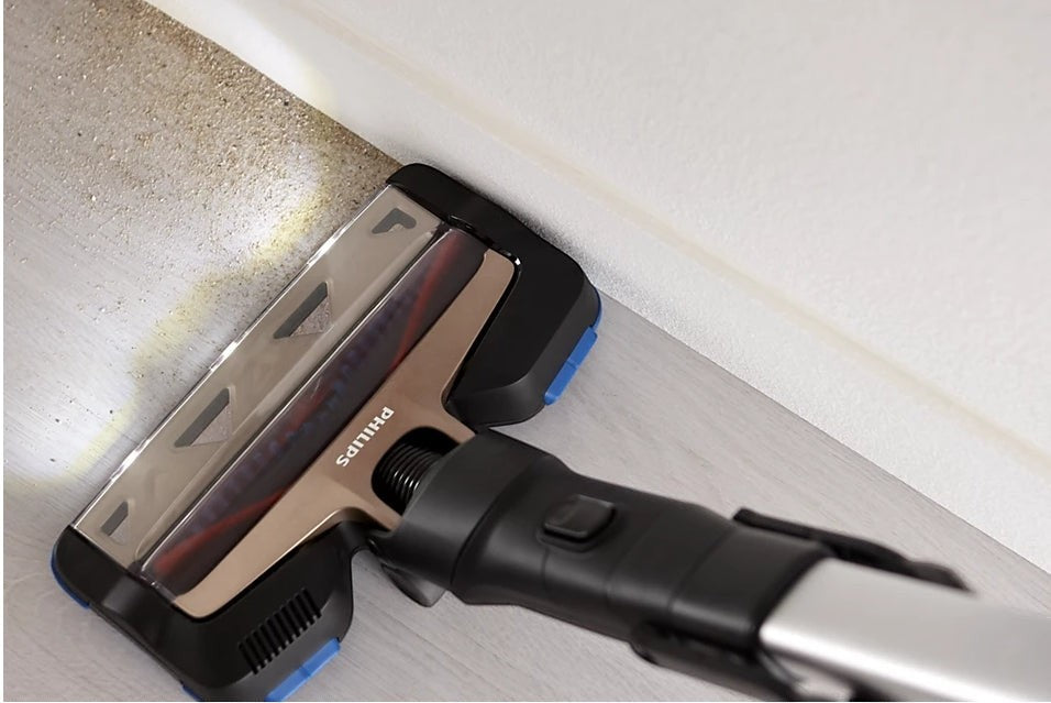 Taghareed Philips SpeedPro Max vacuum cleaner head with LED lights cleaning dust from floor edge.