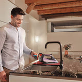 Man using a steam iron on a kitchen counter with wooden beams in the background