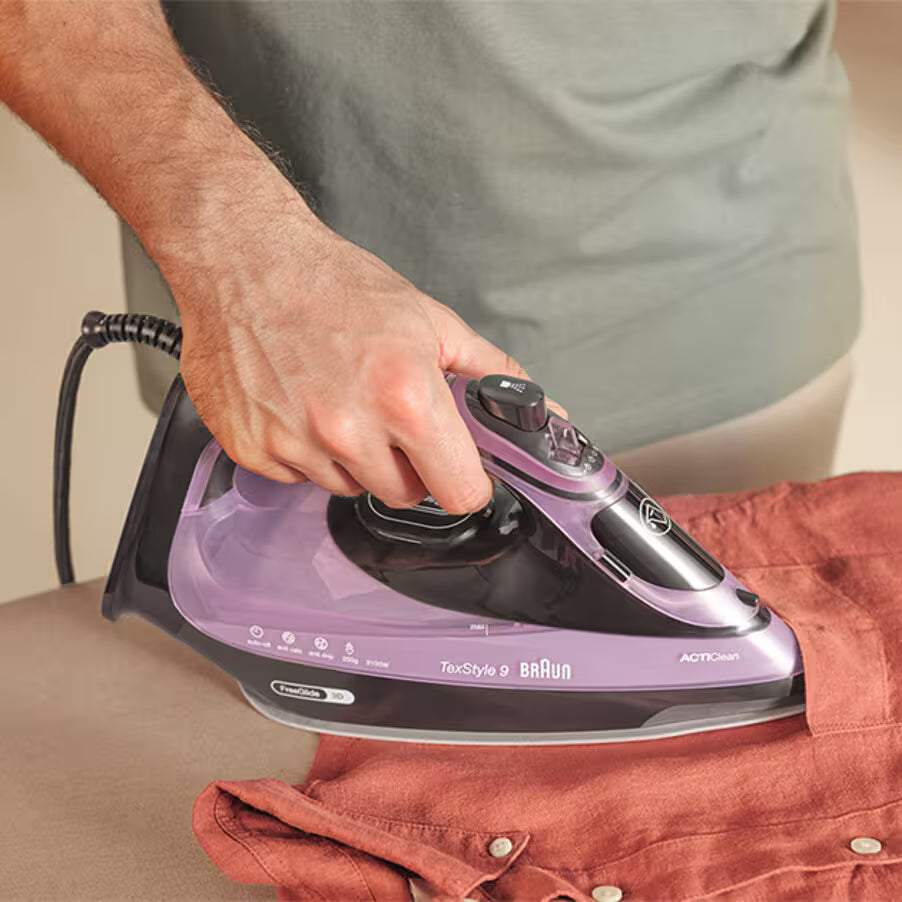Person ironing a shirt with a Braun steam iron.