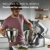 Person using a stand mixer with large bowls in a kitchen setting