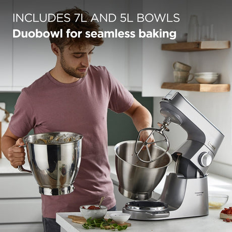 Person using a stand mixer with large bowls in a kitchen setting