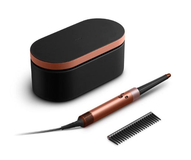 A hair styling tool set on a white background, featuring a black oval charging case with a metallic copper band, a matching copper and black styling wand, and a black comb.