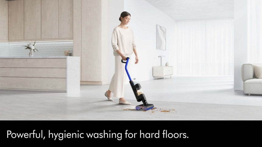 A woman in a bright, modern living room uses a cordless floor cleaner on a light-colored floor. The image includes a black banner at the bottom with the text 'Powerful, hygienic washing for hard floors.