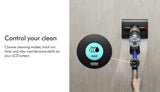 A hand holds a cordless vacuum cleaner against a wall while a separate round touchscreen controller displays a blue MAX icon. Text on the left reads 'Control your clean' with descriptive copy about cleaning modes, run time, and maintenance alerts on an LCD screen.