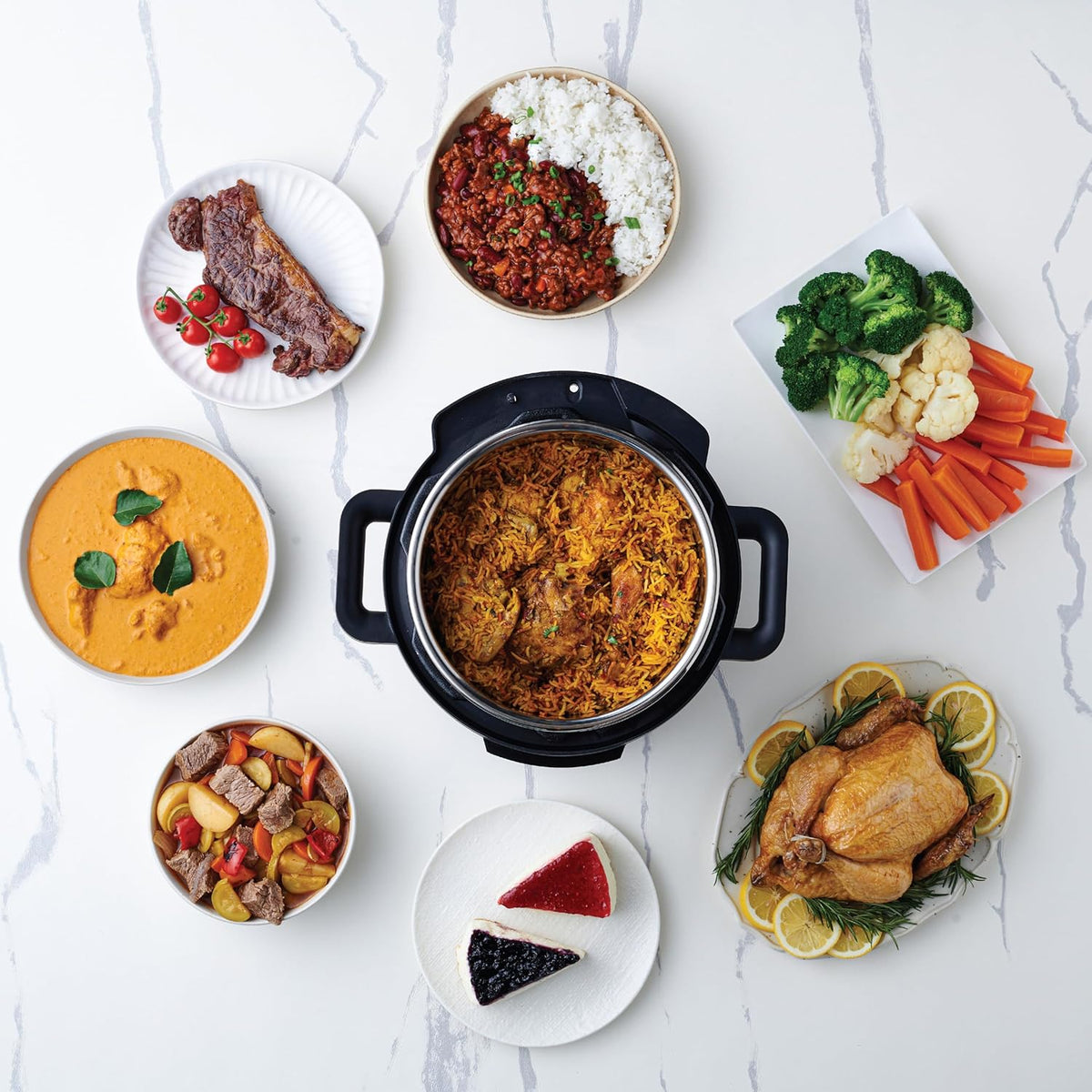 Assorted dishes including a pot of food, vegetables, and desserts on a white surface.