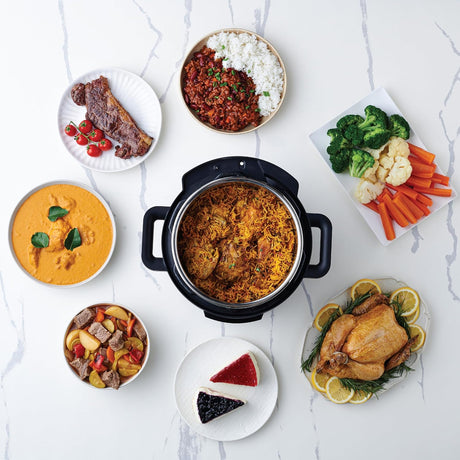 Assorted dishes including a pot of food, vegetables, and desserts on a white surface.