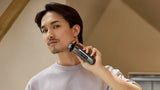 Man using an electric shaver in a neutral indoor setting
