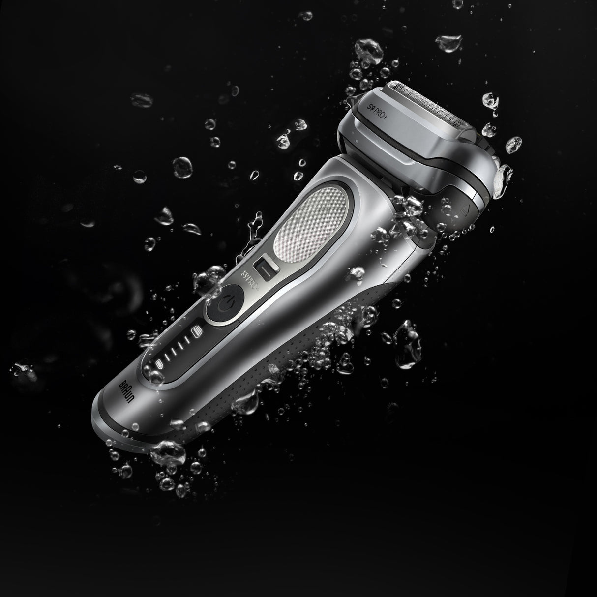 Silver electric shaver with water droplets on a black background