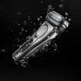 Silver electric shaver with water droplets on a black background