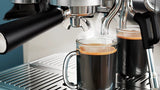 Taghareed Barista Brew semi-automatic espresso machine brewing espresso into a glass mug. Stainless steel.