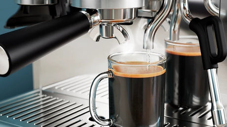 Taghareed Barista Brew semi-automatic espresso machine brewing espresso into a glass mug. Stainless steel.
