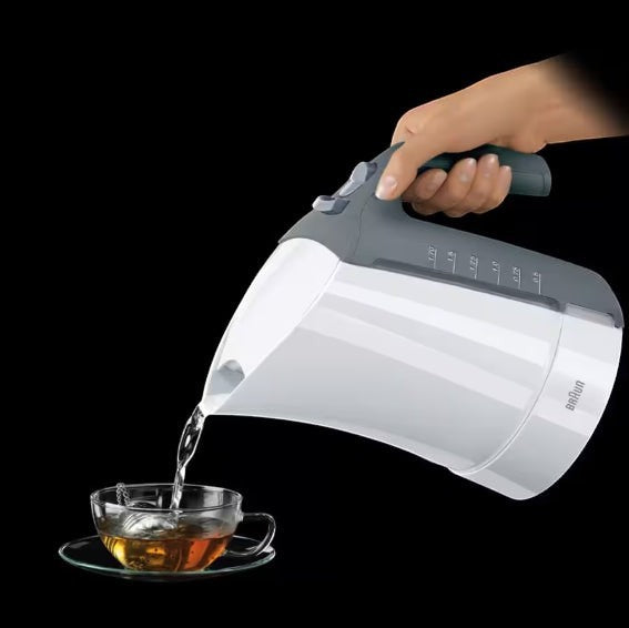 Taghareed Braun electric kettle pouring hot water into a glass cup with tea leaves.
