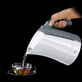 Taghareed Braun electric kettle pouring hot water into a glass cup with tea leaves.