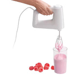 Taghareed Braun MultiMix 3 HM3137WH white 500W hand mixer with whisk attachments making pink batter in a glass, with raspberries.
