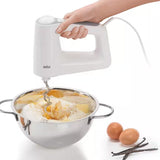 Taghareed Braun MultiMix 3 hand mixer in white, with dough hook mixing ingredients in a stainless steel bowl. Includes eggs and vanilla beans.
