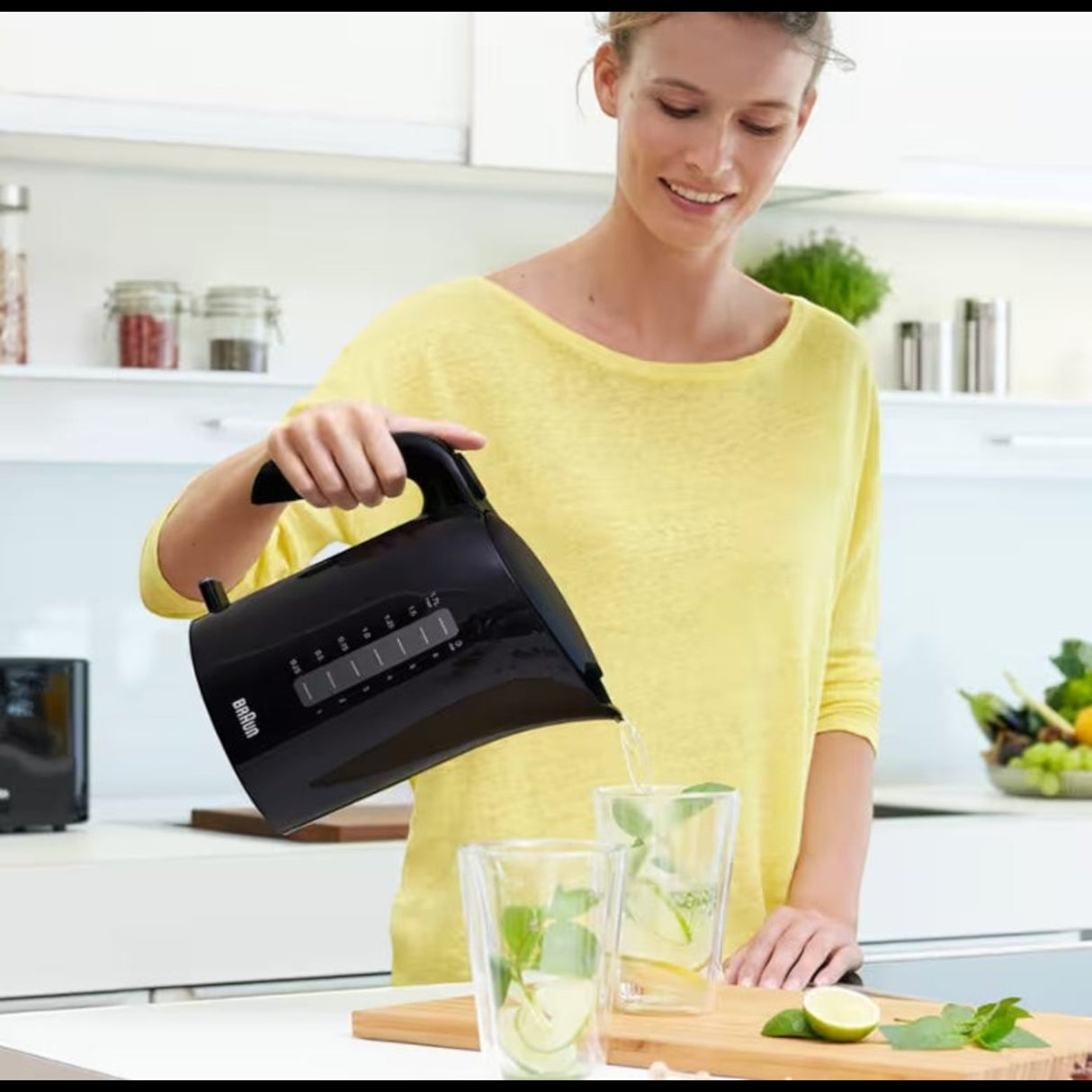 Taghareed Braun PurEase black 1.7L electric kettle pouring water into glasses with mint and lemon