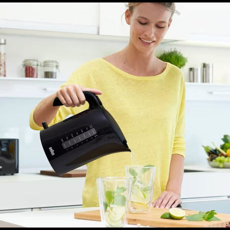 Taghareed Braun PurEase black 1.7L electric kettle pouring water into glasses with mint and lemon