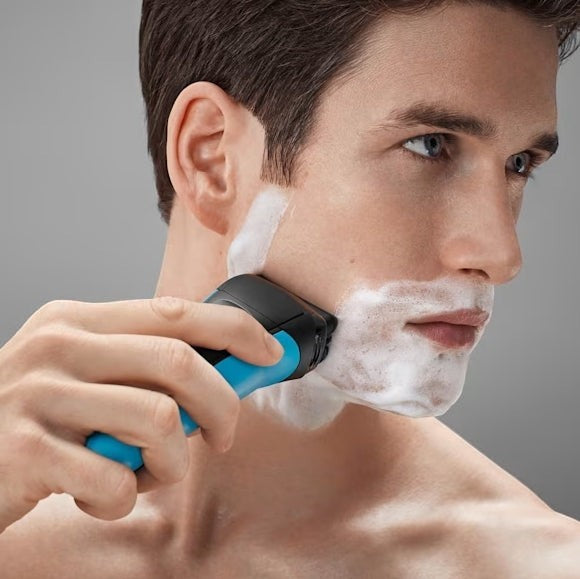 Braun Series 3 310s black and blue electric shaver with foam on a man's face