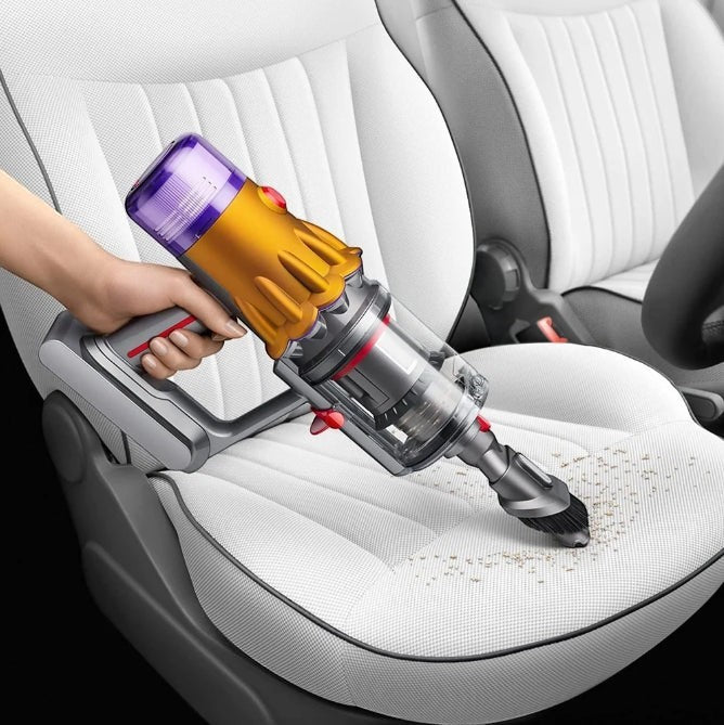 Taghareed cordless stick vacuum cleaner with yellow and purple body, cleaning car seat.