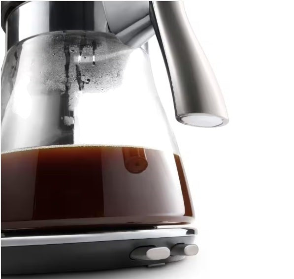 Taghareed De'Longhi Clessidra filter coffee maker with glass carafe filled with coffee, stainless steel handle.