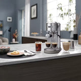 Taghareed De'Longhi Dedica Duo stainless steel espresso machine with cold brew option and steam wand, making coffee.