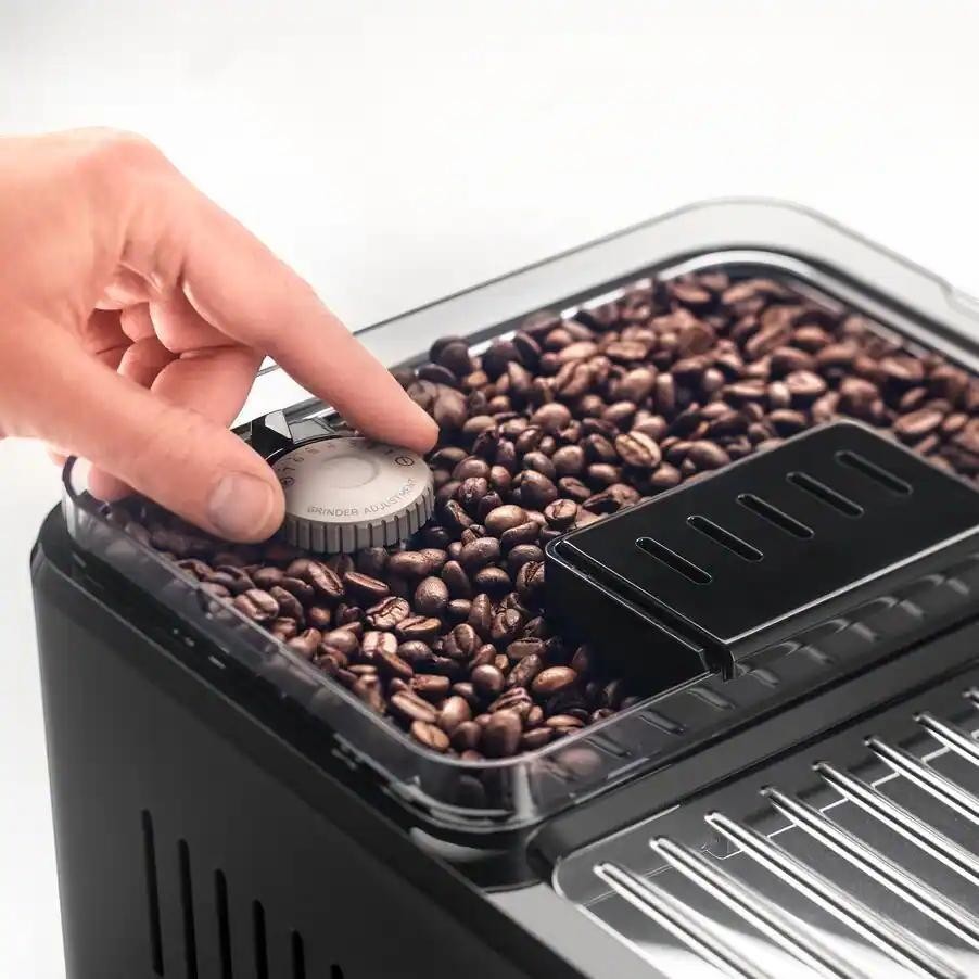 Taghareed De'Longhi Eletta Explore coffee machine bean hopper with grinder adjustment dial being turned.