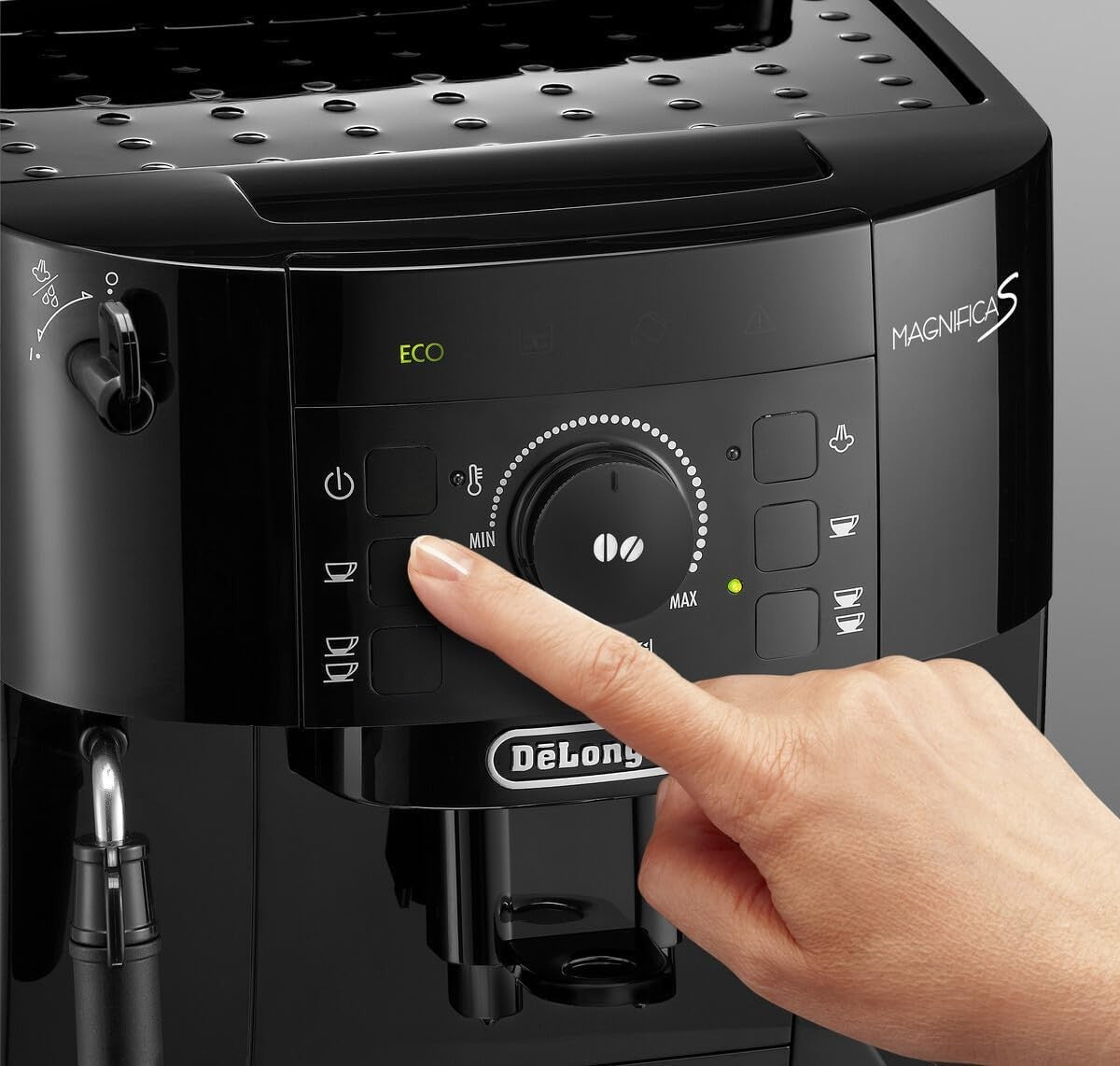 Taghareed De'Longhi Magnifica S black automatic coffee machine with a finger pressing a button.