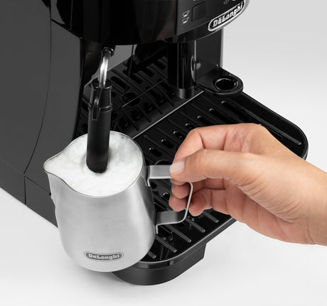 Taghareed De'Longhi Magnifica S black automatic coffee machine frothing milk with a stainless steel pitcher.