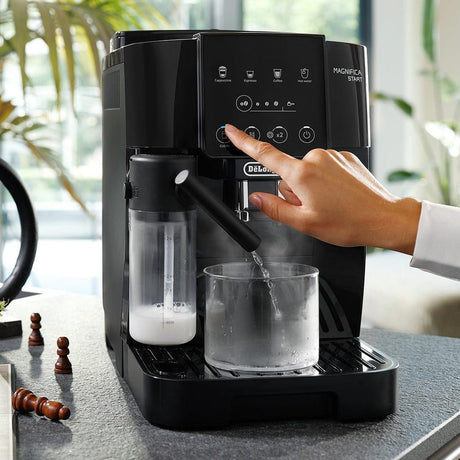 Taghareed De'Longhi Magnifica Start automatic coffee machine with milk frother, dispensing hot water into a glass.