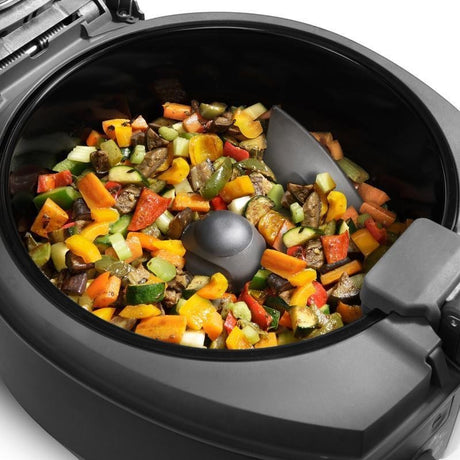Taghareed De'Longhi MultiFry Extra Chef air fryer with mixed vegetables including peppers, zucchini, and carrots, featuring an automatic stirring paddle.
