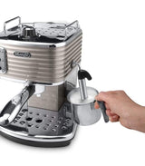 Taghareed De'Longhi Scultura espresso machine in beige with chrome accents, frothing milk in a stainless steel pitcher.