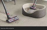 Taghareed Dyson V12s Detect Slim Submarine cordless vacuum cleaning debris and pet hair from carpet and a dog bed.