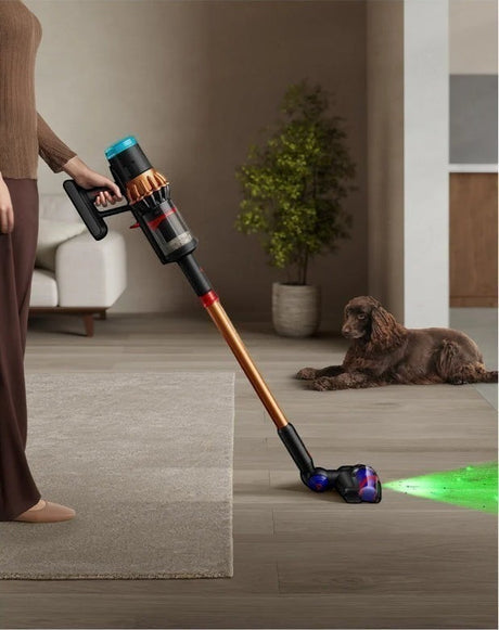 Taghareed Dyson V16 Piston Animal Submarine cordless vacuum in copper and black, with wet roller head cleaning floor.