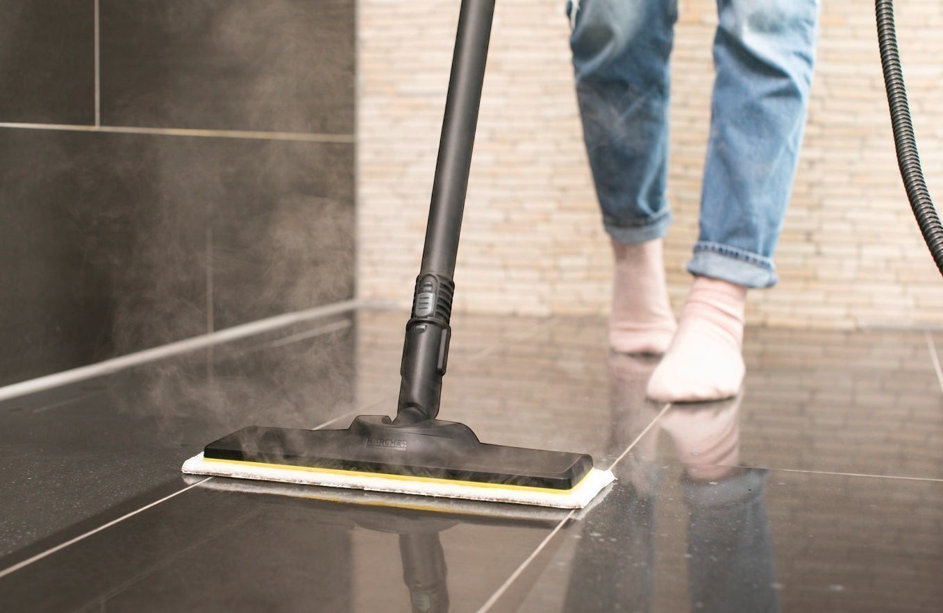Taghareed Karcher SC 4 EasyFix steam cleaner with floor head cleaning dark tiled floor, emitting steam.