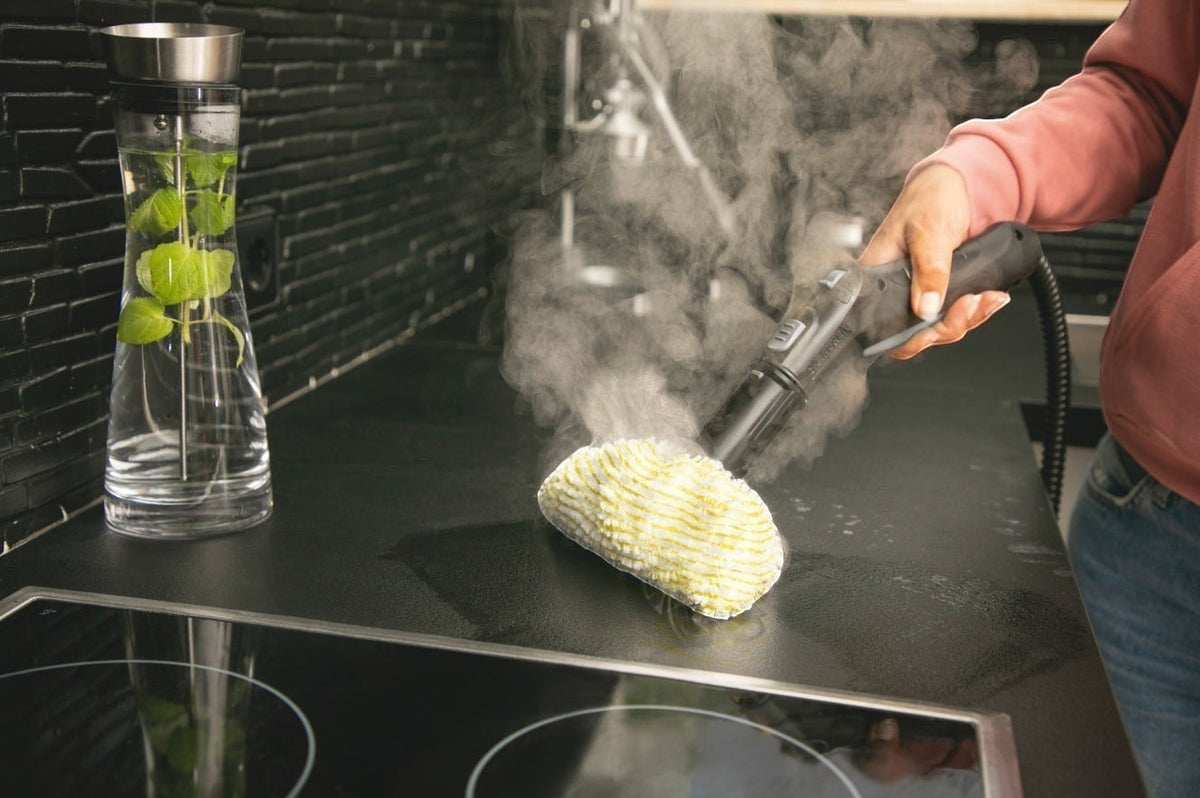 Taghareed Karcher SC 4 EasyFix steam cleaner with yellow microfiber pad cleaning a black stovetop. Steam is visible.