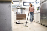 Taghareed Karcher SC 4 EasyFix steam cleaner with floor nozzle cleaning a tiled kitchen floor. White and yellow unit.