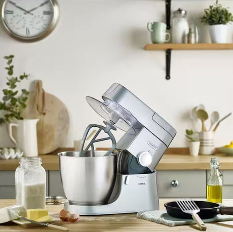 Taghareed silver Kenwood Chef XL stand mixer with 6.7L stainless steel bowl and beater attachment, 1200W motor.