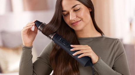 Taghareed Philips 5000 Series black air styler with 38mm ThermoBrush attachment, used by a woman with long brown hair.