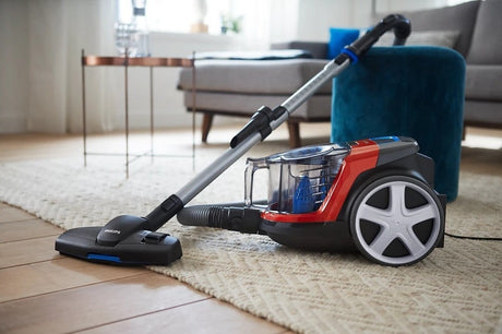 Taghareed Philips PowerPro Compact bagless vacuum cleaner in red and black with a MultiClean nozzle on a rug.