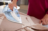 Taghareed Philips 7000 Series steam iron, light blue and white, with SteamGlide Plus soleplate, used on a beige garment.