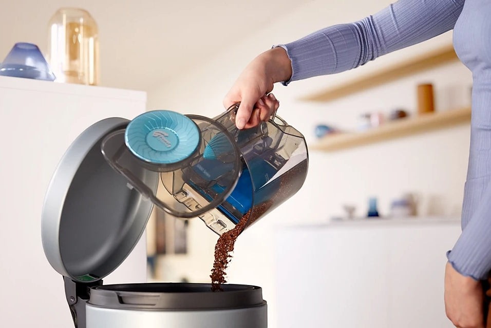 Taghareed Philips 5000 Series bagless vacuum cleaner dustbin being emptied. Blue accents.
